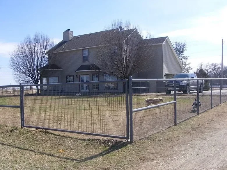 Steel frame and wire mesh perimeter fencing around residential property with metal gate