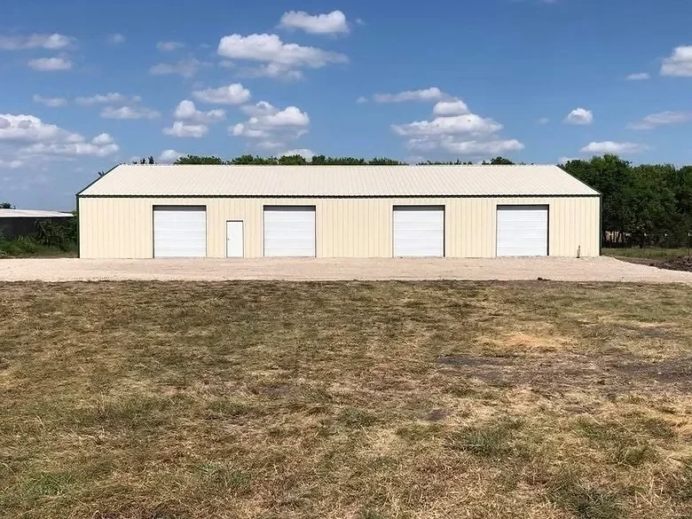 Concrete pad and foundation for metal building with white garage doors