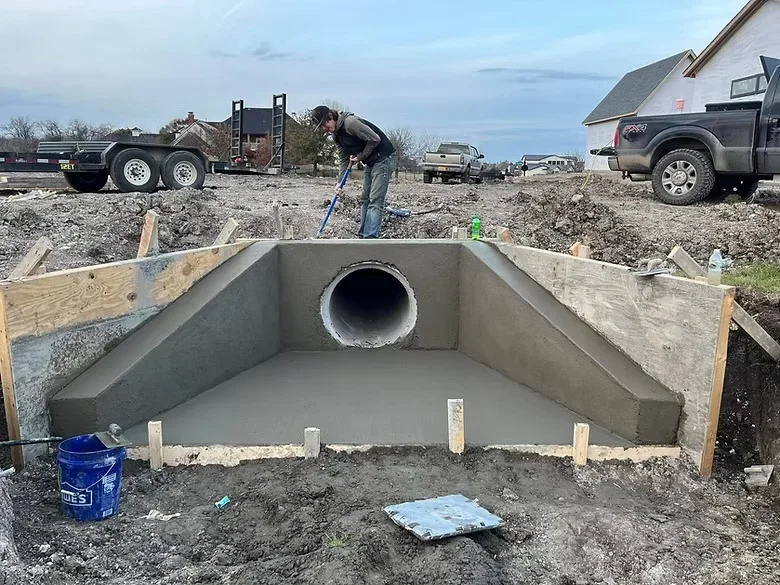 Precast concrete culvert with pipe opening installed in excavated foundation with wooden forms