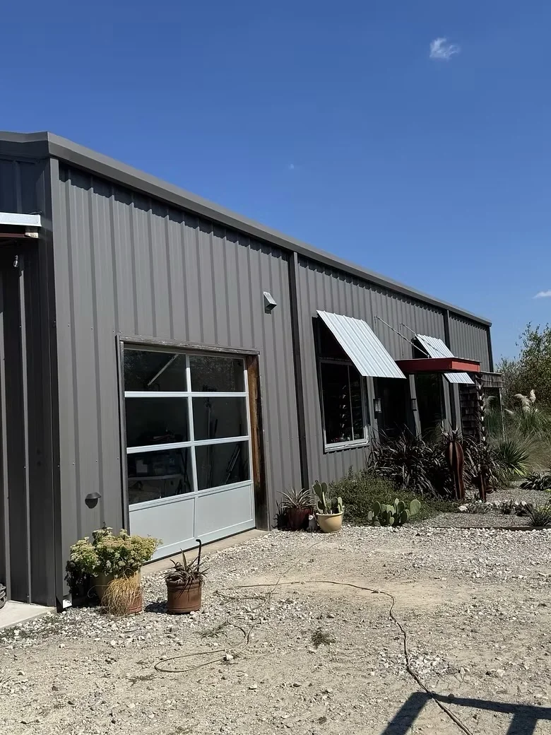 Metal building with corrugated steel siding, aluminum windows, and metal awnings on concrete foundation