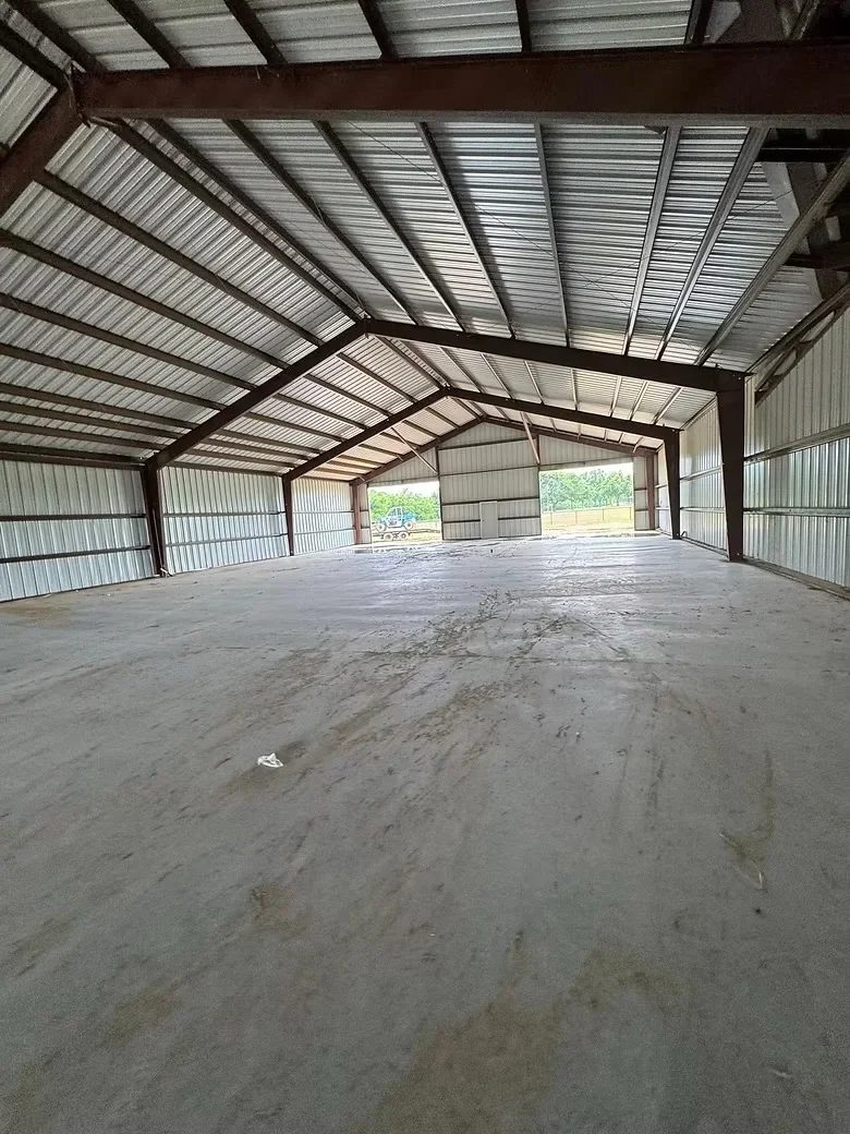 Concrete slab foundation in metal-frame agricultural building with corrugated metal roof and walls