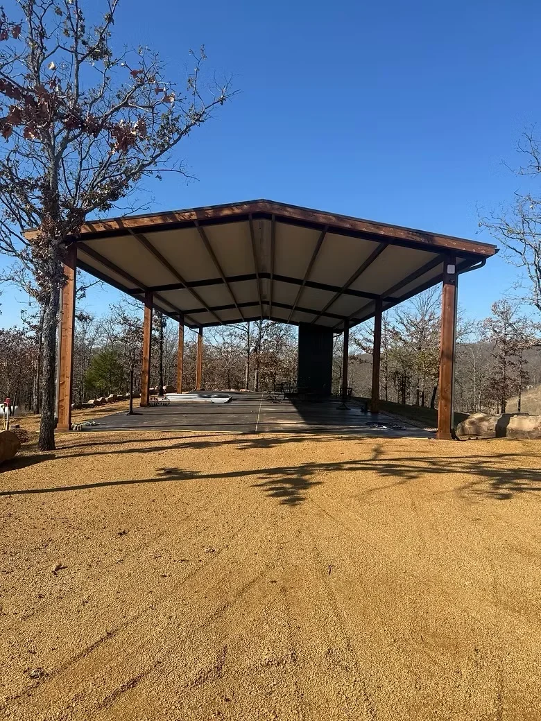 Metal carport with steel frame, roof panels, and concrete foundation on gravel pad