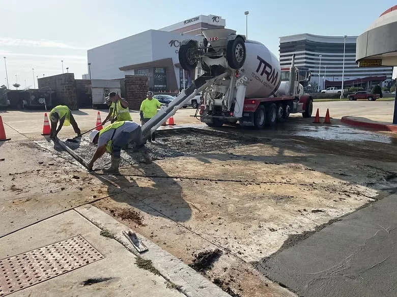 Concrete removal crew using vacuum truck to clear broken concrete from commercial lot