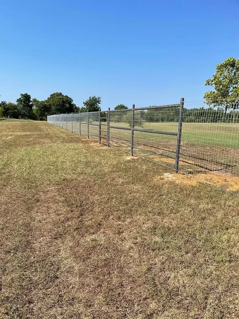 Metal ranch fencing with concrete post footings installed in pasture