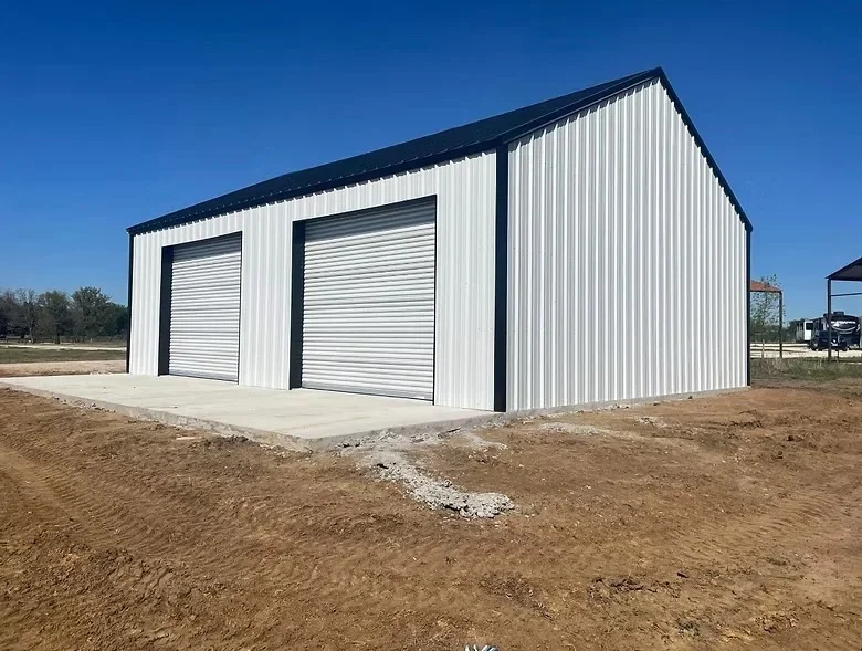 White metal building with concrete foundation and pad, two roll-up doors