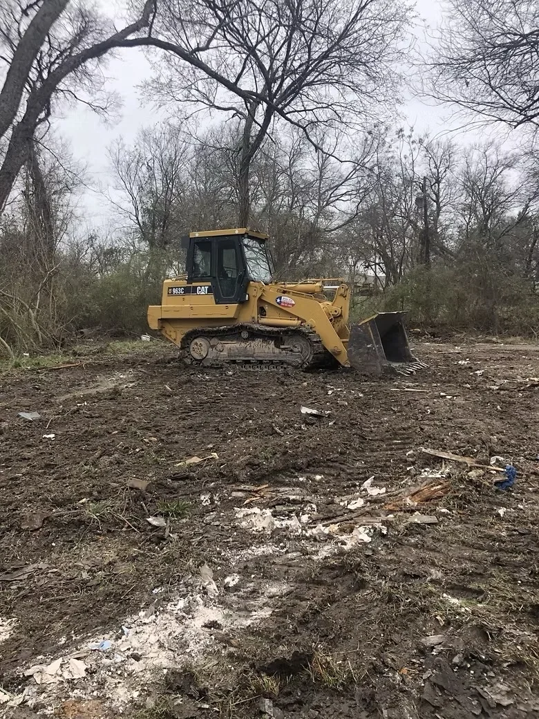 Cat track loader clearing debris and vegetation from wooded site