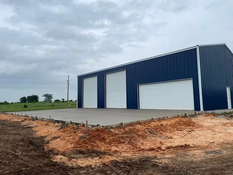 Concrete foundation and apron for metal agricultural building with three bay doors